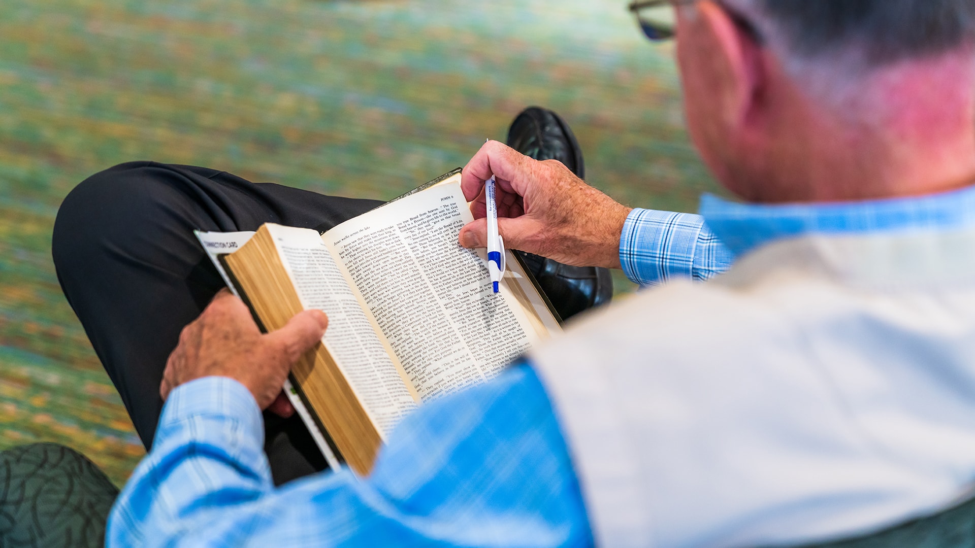 A man, pen in hand, reading his Bible at Brookwood Church